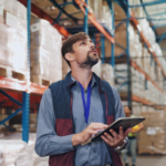 Gestor logístico dentro de armazém com tablet na mão fazendo o planejamento logístico de 2026