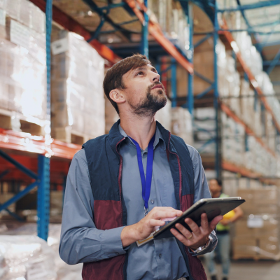 Gestor logístico dentro de armazém com tablet na mão fazendo o planejamento logístico de 2026